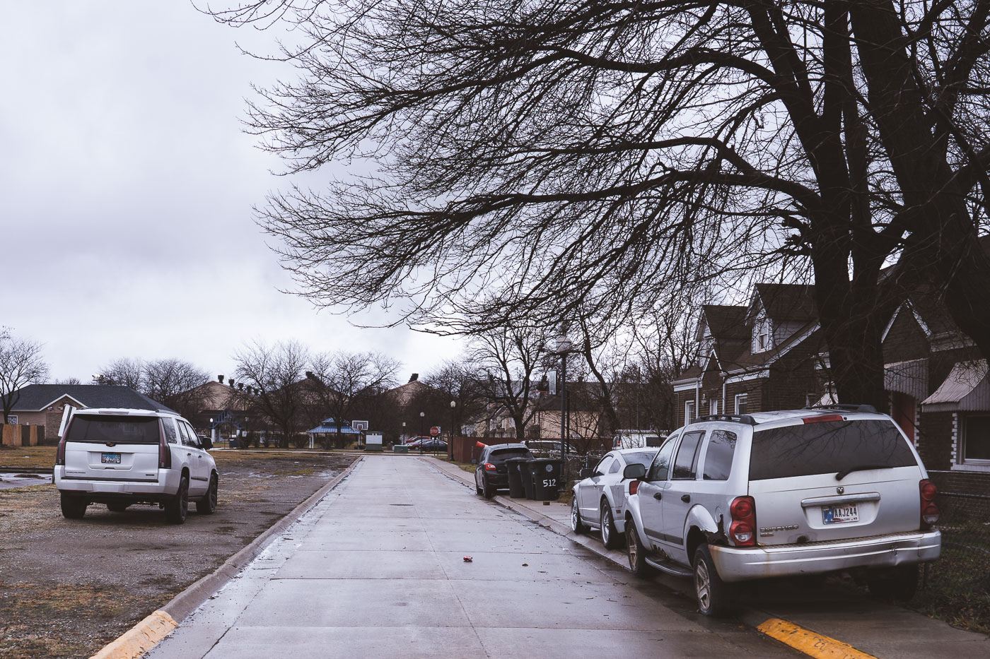 Park Street in Marktown, Indiana, a historic company town, shows residential housing and parked vehicles under a cloudy sky.