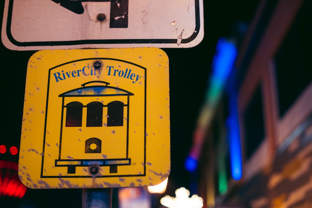 Weathered yellow RiverCity Trolley sign on Hennepin Avenue in Uptown Minneapolis at night.