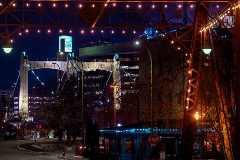 Merriam Street Bridge lit up at night 1 Hennepin Ave Bridge, seen from the Merriam Street Bridge to Nicollet Island. The Merriam bridge dates back to 1887, the now decorative truss span is actually a saved portion of the former Broadway Ave bridge. It was moved here 100 years later in 1987. (Minneapolis, January 2024)