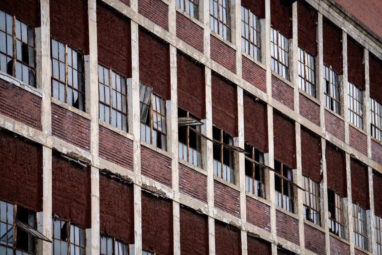 Abandoned Barber-Colman textile machinery factory with red brick facade and white concrete grid framework in Rockford, Illinois.
