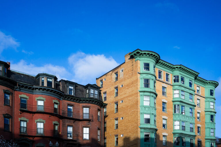 South End Brownstones on Massachusetts Avenue 3 Along Massachusetts Avenue in Boston’s South End, these adjoining brownstones showcase the neighborhood’s signature Victorian-era architecture—ornate bay windows, intricate cornices, and rich brickwork that reflect the city’s 19th-century building boom. The red and tan façades, accented with distinctive green trim, represent the area’s architectural diversity, where Italianate and Renaissance Revival influences meet. Once part of a working-class district and now one of Boston’s most carefully preserved historic neighborhoods, the South End’s rowhouses remain a defining feature of the city’s urban identity and charm.