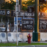 Signs hang on the fencing around the Minneapolis Police 3rd Precinct police station. The station burned 4 years ago on this day.