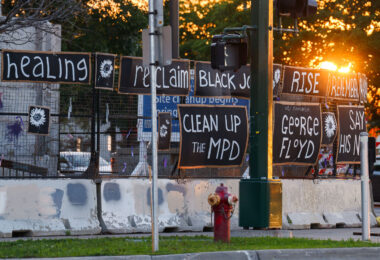Signs hang on the fencing around the Minneapolis Police 3rd Precinct police station. The station burned 4 years ago on this day.