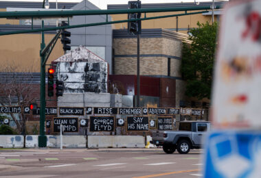 Signs hang on the Minneapolis police 3rd precinct police station on the 4 year anniversary of protesters burning it.
