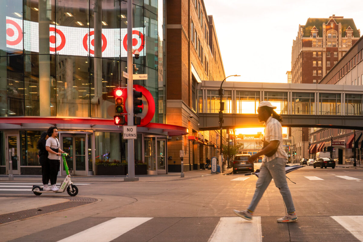 A scotter and a man walks on Nicollet Mall during a June 2024 sunset.