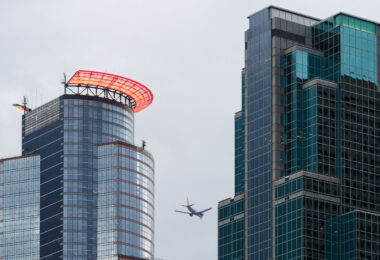 A Sun Country Airlines plane flies above downtown Minneapolis.