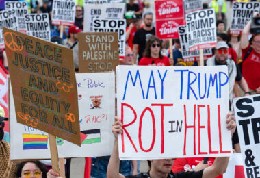 Protester holds up a sign that reads "May Trump Rot in Hell" at a march outside the 2024 Republican National Convention.