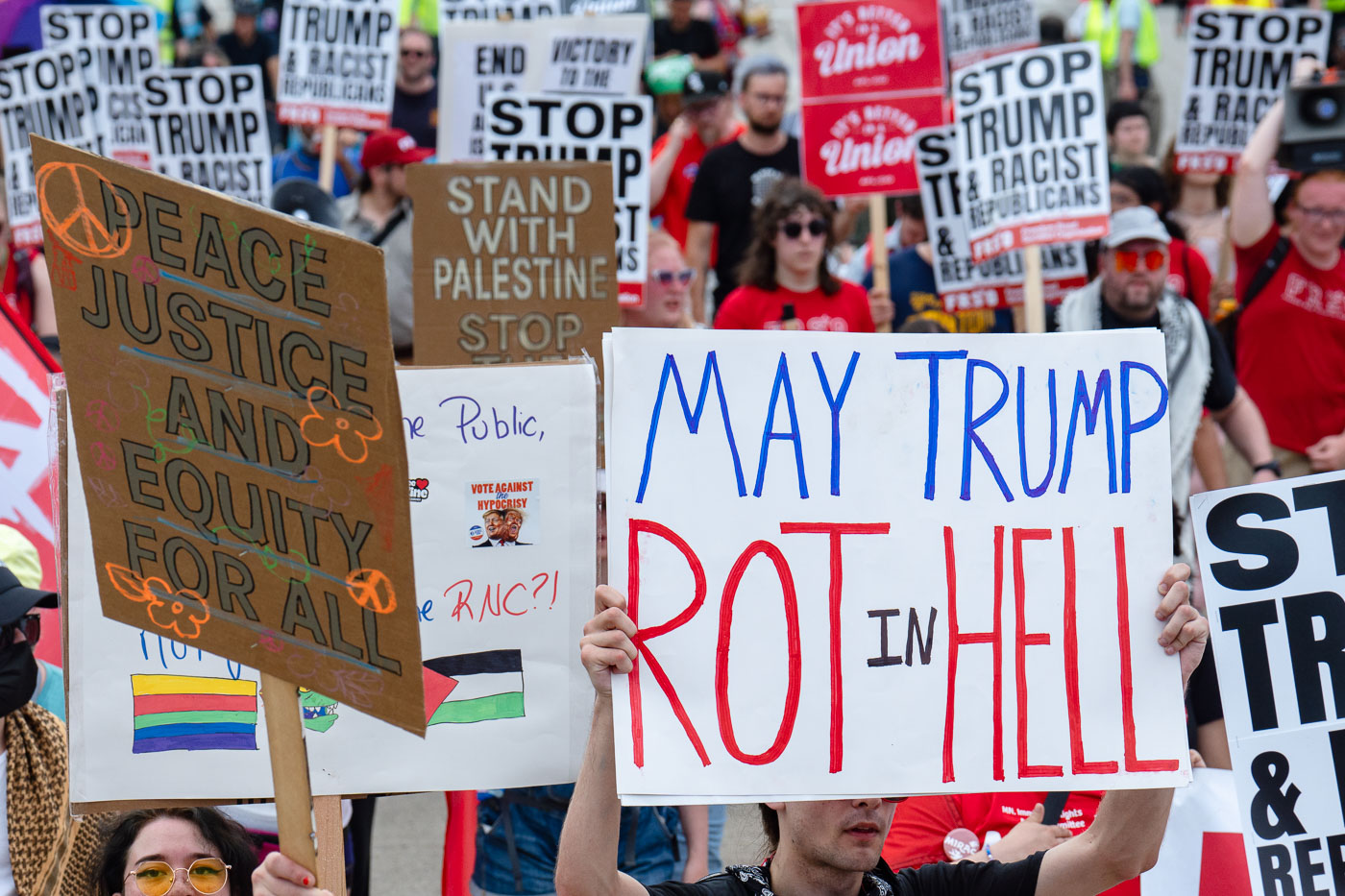 Protester holds up a sign that reads "May Trump Rot in Hell" at a march outside the 2024 Republican National Convention.