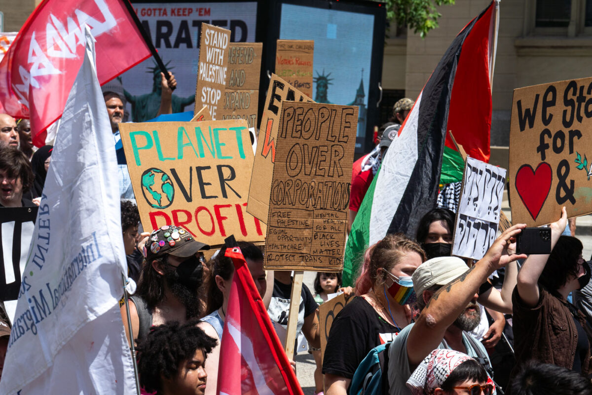 Protesters at the 2024 RNC in Milwaukee. Holding signs that read "Planet over profit", "People over corporations", "Stand with Palestine".