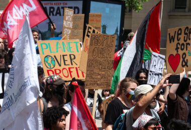 Protesters at the 2024 RNC in Milwaukee. Holding signs that read "Planet over profit", "People over corporations", "Stand with Palestine".