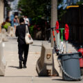 A woman walks down the sidewalk that's filled with concrete barriers and security fencing near the Pfister Hotel.