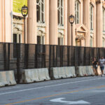 A couple walk outside security fencing surrounding theMilwaukee County Historical Society. The city is heavily secured during the 2024 Republican National Convention.