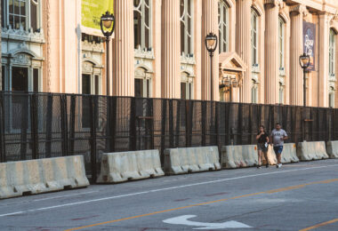 A couple walk outside security fencing surrounding theMilwaukee County Historical Society. The city is heavily secured during the 2024 Republican National Convention.