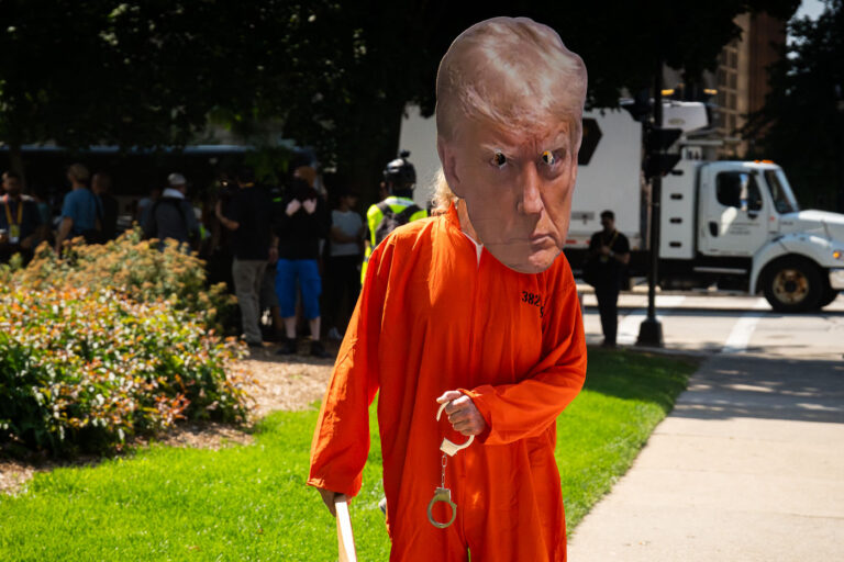 Donald Trump in orange and handcuffs 1 A man dressed as Donald Trump in jail uniform with handcuffs outside the Republican National Convention.