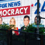 Large Fox News billboard on the side of a building outside the 2024 Republican National Convention. Security fencing visible in the foreground.