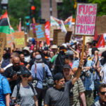 A man holds up a "Fuck Donald Trump" protest sign at a march outside the 2024 Republican National Convention.