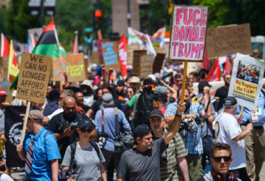 A man holds up a "Fuck Donald Trump" protest sign at a march outside the 2024 Republican National Convention.