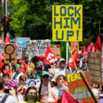 Protester holds up a sign reading "Lock Him Up!" at a march around the 2024 Republican National Convention in Milwaukee.