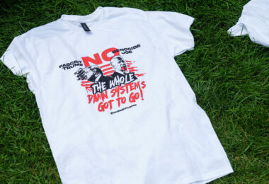 A t-shirt in the grass at the 2024 Republican National Convention. It reads No Genocide Joe No Fascist Trump. The whole damn system's got to go! Shirt from The Revolutionary Communist Party.