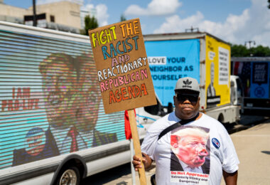 Anthony Johnson holds up a sign that reads "Fight the racist and reactionary republican agenda" outside the 2024 Republican National Convention in Milwaukee.