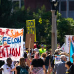A woman holds up her protest sign outside the Republican National Convention prior to a march to the secure perimeter.