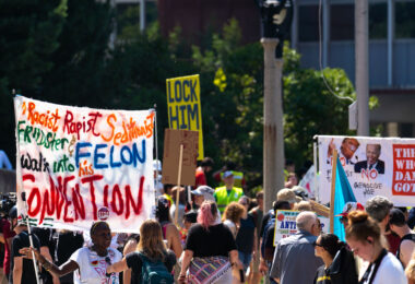A woman holds up her protest sign outside the Republican National Convention prior to a march to the secure perimeter.