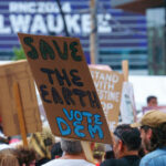 Protester holding up a sign that reads "Save the Earth Vote Dem" during a march during the 2024 Republican National Convention in Milwaukee.