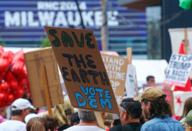 Protester holding up a sign that reads "Save the Earth Vote Dem" during a march during the 2024 Republican National Convention in Milwaukee.