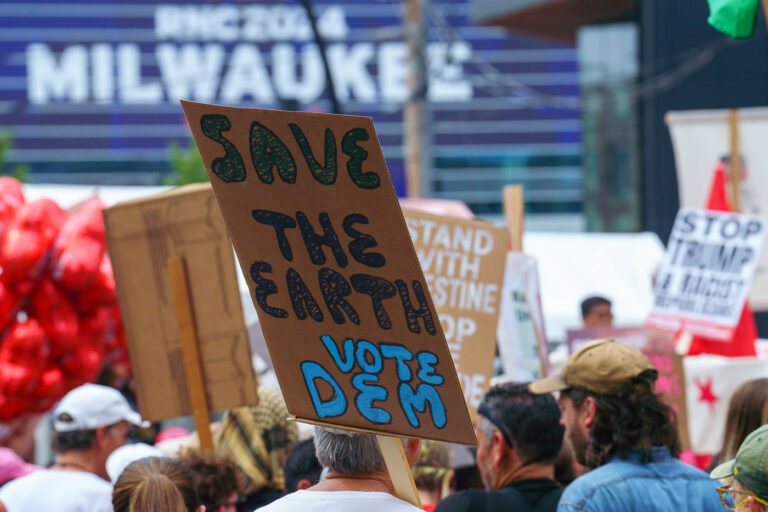 Save the Earth Vote Dem 2 Protester holding up a sign that reads "Save the Earth Vote Dem" during a march during the 2024 Republican National Convention in Milwaukee.