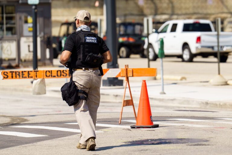 U.S. Secret Service Secures Street Perimeter During 2024 Republi 4 A U.S. Secret Service officer monitors a restricted intersection near the convention perimeter in Milwaukee during the 2024 RNC. Temporary street closures and layered fencing systems surrounded the Fiserv Forum complex, part of a federally designated National Special Security Event. Agents and uniformed officers coordinated with local police to maintain traffic control and manage credentialed access in secure areas throughout the downtown core.