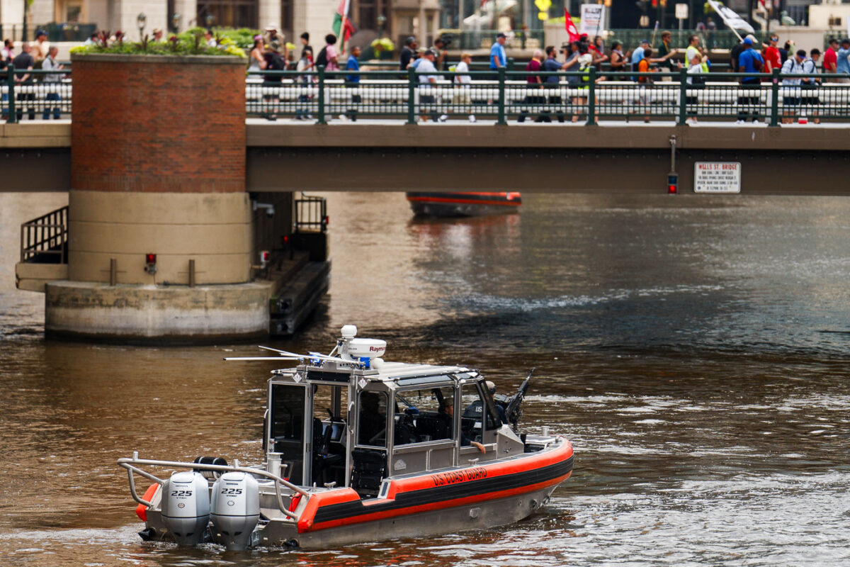 The United States Coast Guard in the Milwaukee River as protesters march over the bridge towards the 2024 Republican National Convention.