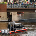 The United States Coast Guard in the Milwaukee River as protesters march over the bridge towards the 2024 Republican National Convention.