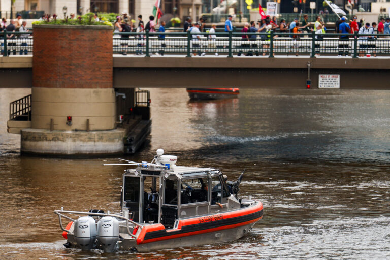 U.S. Coast Guard Patrol on the Milwaukee River 1 A U.S. Coast Guard patrol boat equipped with twin outboard engines and mounted equipment navigates the Milwaukee River beneath the Wells Street Bridge. The vessel formed part of the multi-agency security perimeter surrounding the 2024 Republican National Convention, with maritime units maintaining a visible presence along the riverfront as protesters and delegates converged downtown.