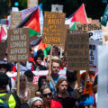 Protesters hold up signs as they march around the 2024 Republican National Convention in Milwaukee.