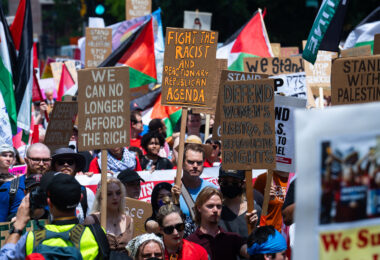 Protesters hold up signs as they march around the 2024 Republican National Convention in Milwaukee.