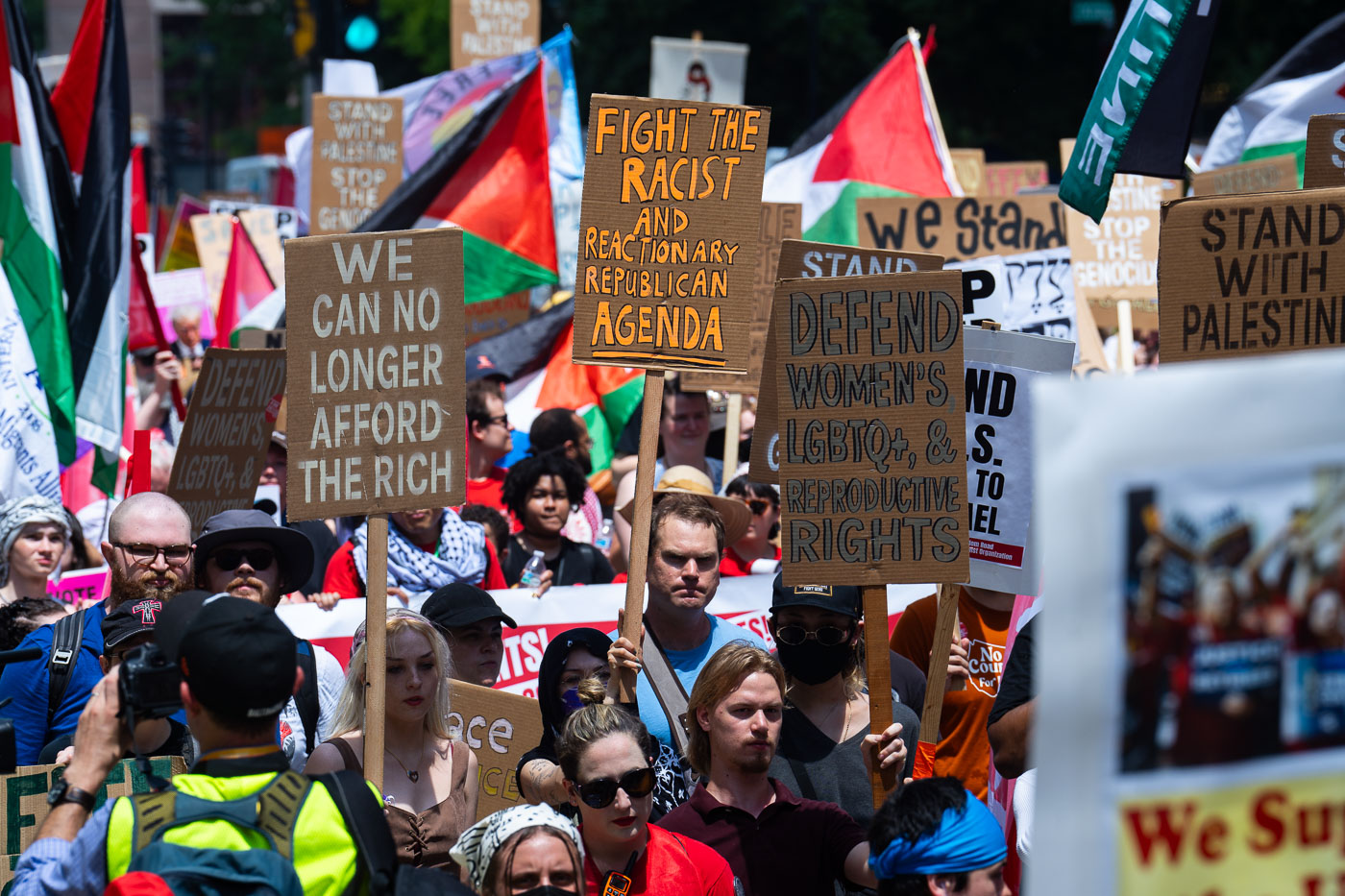 Protesters hold up signs as they march around the 2024 Republican National Convention in Milwaukee.