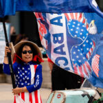 A woman dressed in American flag attire holds a Trump flag outside the 2024 Republican National Convention in Milwaukee.