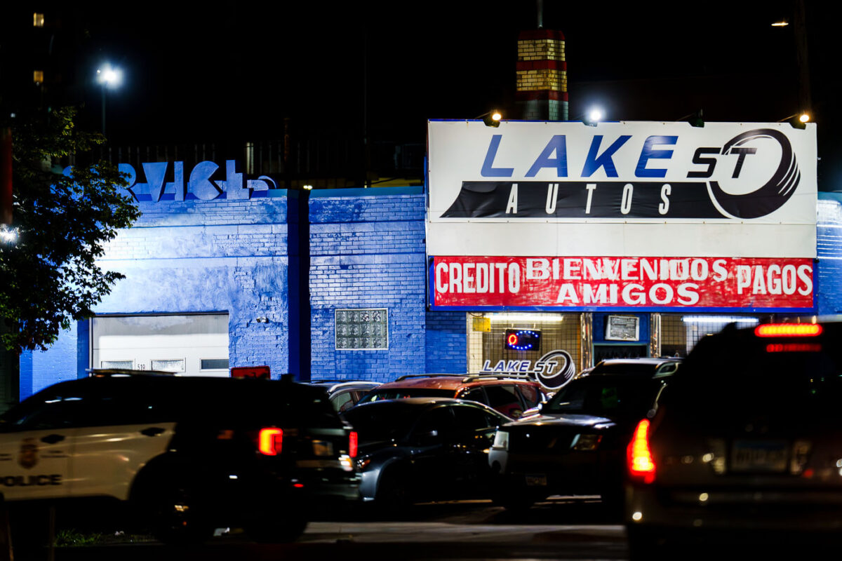 A Minneapolis police squad car drives down Lake Street in front of Lake St Autos.