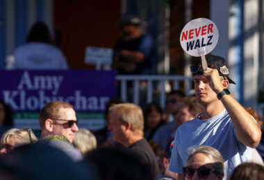 A man holds up a "Never Walz" sign on a stick at the Minnesota State Fair outside where Governor and Vice Presidential Candidate Tim Walz was going to make an appearance.