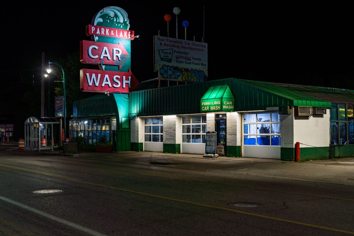 Park & Lake Car Wash neon sign illuminates a green and white building on Lake Street in Minneapolis at night.