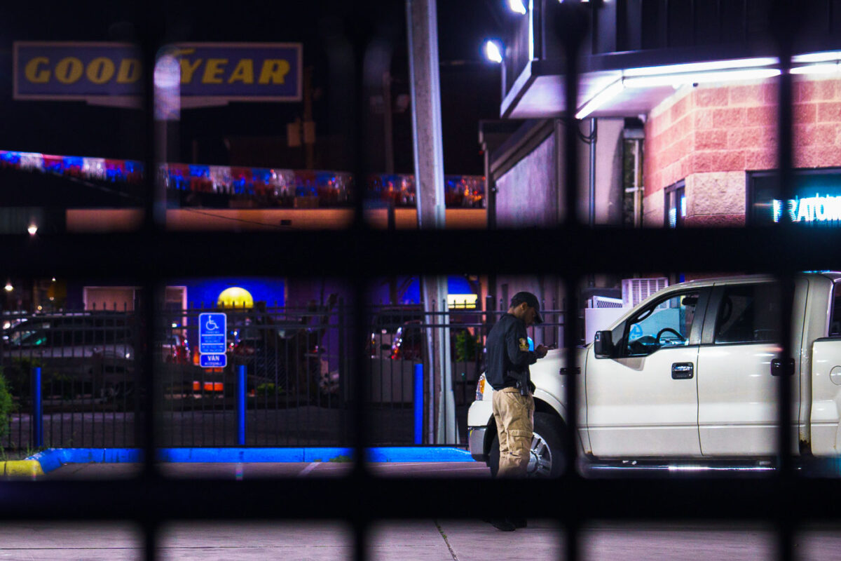 A armed private security guard on his phone inside a fenced off gas station on Lake Street in South Minneapolis.