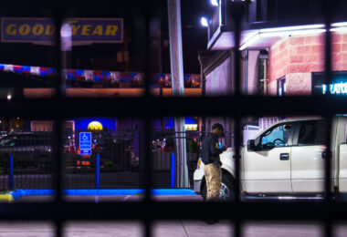 A armed private security guard on his phone inside a fenced off gas station on Lake Street in South Minneapolis.