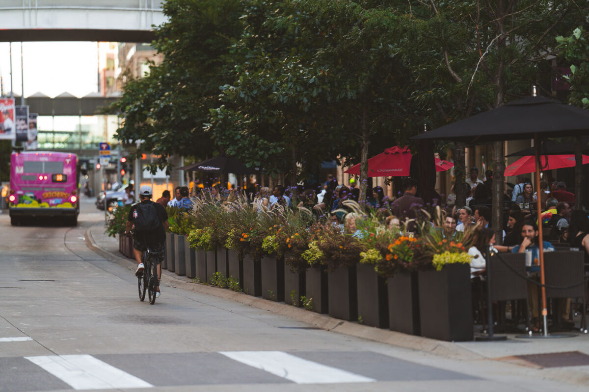 A Thursday evening on Nicollet Mall. Biker passes by The Local restaurant patio at 10th Street. (Downtown Minneapolis, September 2024)