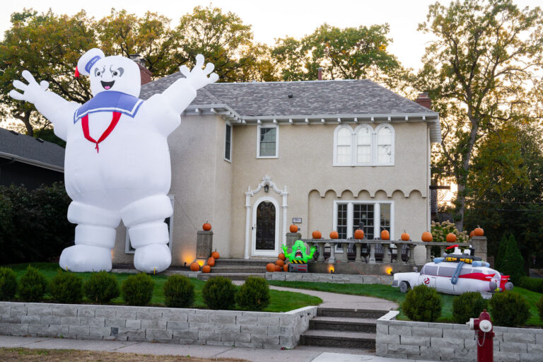 Minneapolis Home Halloween Decorations: Marshmallow Man & Ecto-1 4 A residential property in Minneapolis is adorned with elaborate Halloween decorations, featuring prominent figures from the "Ghostbusters" franchise. The display includes a large inflatable Stay Puft Marshmallow Man and a replica of the Ecto-1 vehicle, alongside numerous pumpkins and a Slimer decoration. This type of extensive home decoration for Halloween has become a cultural practice in many communities, transforming private residences into temporary public attractions during the holiday season. The "Ghostbusters" theme, popular since the 1984 film, continues to resonate, inspiring creative displays like this one.