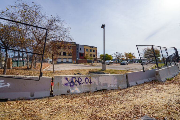 Minneapolis Police 3rd Precinct Redevelopment Begins 2 Construction fencing and concrete barriers surround the Minneapolis Police Third Precinct building, which is undergoing redevelopment. The precinct was famously damaged by fire during protests following the murder of George Floyd in May 2020. The city plans to transform the site into a "Democracy Center" intended to house election services and community spaces. This redevelopment marks a significant shift for a building that became a focal point of public unrest and a symbol of community anger.