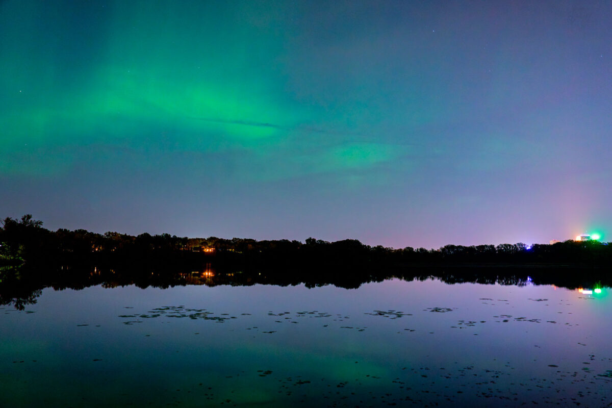 Northern lights above Cedar Lake in Minneapolis. The downtown Minneapolis skyline visible in the background.