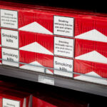 Duty-Free Display of Marlboro Cigarettes at Puerto Vallarta Air 2 Stacks of Marlboro cigarette cartons are arranged neatly in a duty-free shop at Puerto Vallarta International Airport. The bold red-and-white packaging contrasts sharply with the health warnings — “Smoking kills” and “Smoking seriously harms you and others around you.” The display, priced in both U.S. dollars and pesos, reflects international tobacco regulations that require prominent labeling even in airport retail environments catering to travelers.