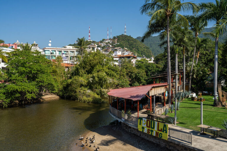 A coin-operated public payphone marked “Monedas 090” stands on a cobblestone street in central Puerto Vallarta, a reminder of the pre-digital era still visible in everyday urban life. Behind it, a mix of aging vehicles, small storefronts, and whitewashed buildings with red-tiled roofs reflect the city’s blend of local tradition and evolving modernity. These relics of analog communication, though seldom used today, remain scattered across Mexico’s towns and resort cities — quiet artifacts of an infrastructure that once connected travelers and locals alike.