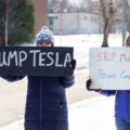 Protesters hold signs that read "Dump Tesla" "Stop Musk's Power Grab!" at a "Tesla Takedown" protest in front of a Tesla facility in Minneapolis on February 22, 2025.