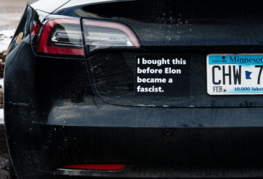 A Tesla vehicle seen in Minneapolis with Tesla branding removed and a sticker reading "I bought this before Elon became a fascist.".